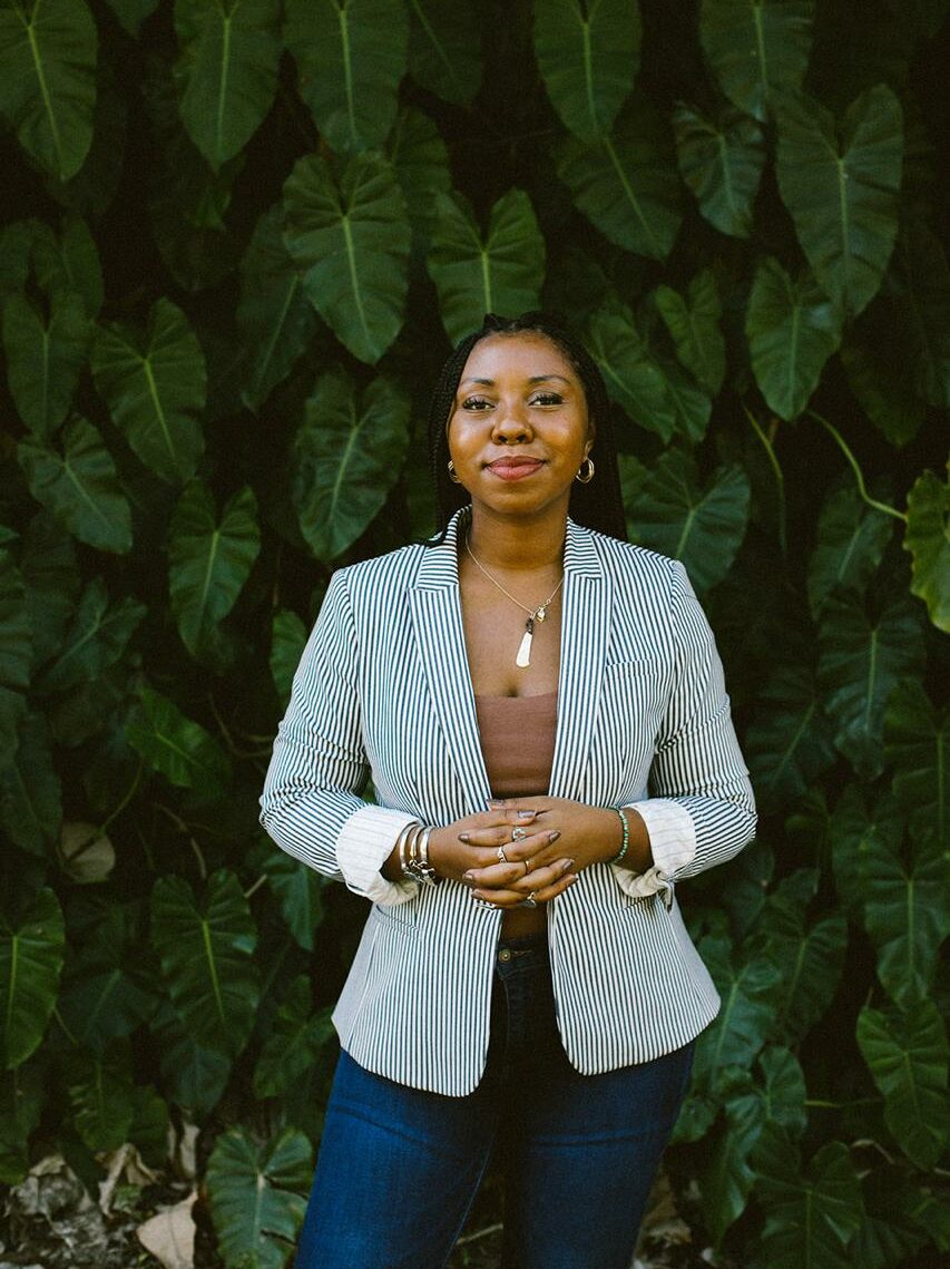 Photo of Dr. Hadiya Sewer in front of a wall of palm leaves